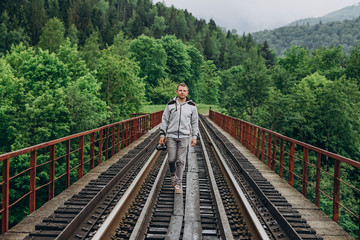Fototapeta premium Young man in a gray tracksuit on a railway track.