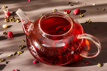 Sunny morning breakfast. Sweet raspberry green tea in glass kettle with dry fruits, flowers and...