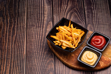 a fries in black dish and two sauces