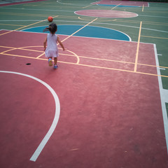 Asian Toddler playing basketball at the basketball court in the evening.