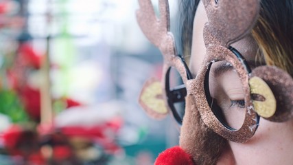 Close up young woman wearing funny Christmas party deer glasses with red nose .Holiday Christmas concept.