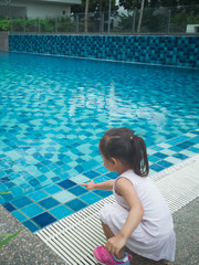Little Asian toddler baby have a fun with a splash near swimming pool