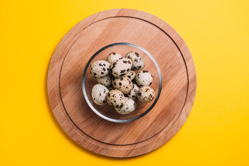 Quail eggs in a plate on a yellow background with place for text.