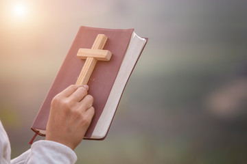 Girl holding the bible and holding a cross Considered as a sacred blessing of God, spirituality and worship and praise from Christians and religious beliefs for blessings.