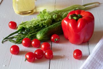 Vegetables and greens for making salad on a white wooden background
