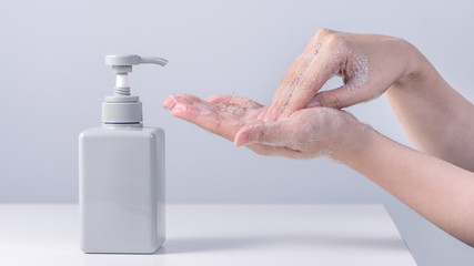 Washing hand. Asian young woman using liquid soap to wash hands, concept of hygiene to stop spreading coronavirus isolated on gray white background, close up.