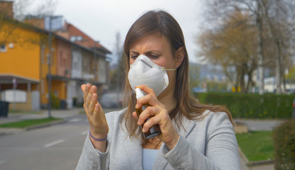 CLOSE UP: Girl disinfects her hands with sanitizing spray before going to work