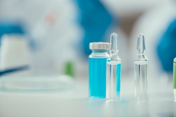 selective focus of ampules near glass container with medicine, covid-19 concept
