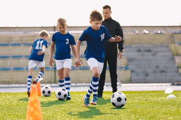 Fototapeta premium Young Boys in Sports Soccer Club on Training Unit. Kids Improve Soccer Skills on Natural Turf Grass Pitch. Football Practice Session for Children Youth Team. Junior Level Professional Soccer School