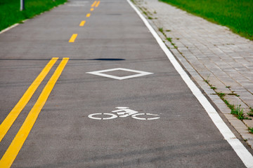 Fototapeta premium Embankment park with green grass and bike lane under blue sky and white clouds