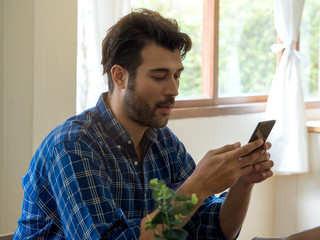 Caucasian man using handphone or mobile phone to communicate, working from home.