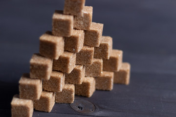 cane brown  sugar cubes in pyramid on black wooden background