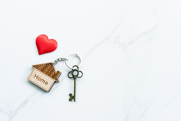 House key with home keyring decorated with mini heart on rusty wood background