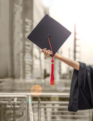 Student proudly holding the cap up into the air after graduation ceremony with vintage color...