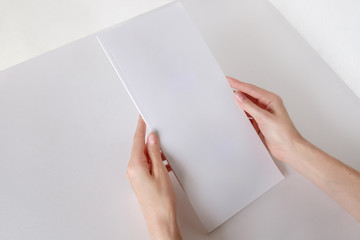 White booklet mockup. Vertical format blank booklet. A woman holds an album with blank pages. Blank cover mocku