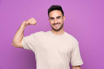 Fototapeta premium Young handsome man over isolated purple background doing strong gesture