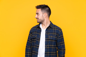 Young handsome man over isolated yellow background looking to the side