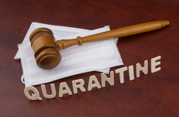 Wooden judge gavel with masks and word quarantine. Law and quarantine concept in time of...