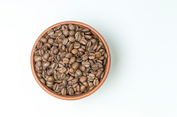 roasted coffee beans in a clay Cup on a white background top view
