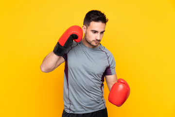 Sport man over isolated yellow wall with boxing gloves