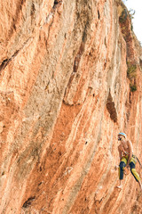 Escalador colgando de cuerda mirando pared