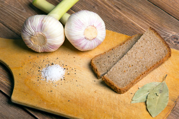 fresh garlic on a wooden board, brown bread and salt
