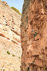 Escalador pequeño en una enorme pared