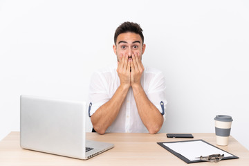 Young business man with a mobile phone in a workplace with surprise facial expression