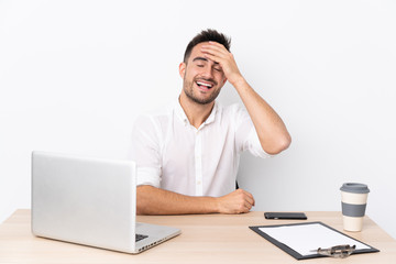 Young business man with a mobile phone in a workplace laughing
