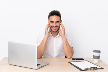 Young business man with a mobile phone in a workplace laughing