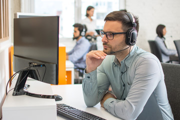 Focused male telephone worker agent working at office
