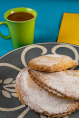 Tree delicious robiols, typical Mallorcan baked sweet recipe, traditional in Easter holiday, and a cup of hot chocolate in the background.