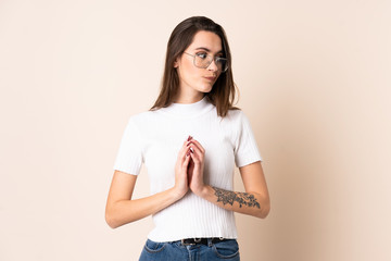 Young woman over isolated beige background scheming something