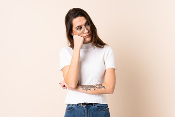 Young woman over isolated beige background with tired and bored expression