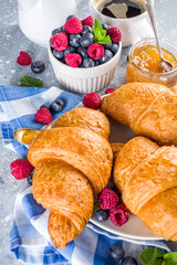 Sweet breakfast butter croissants with coffee cup, orange jam and fresh summer berries. Traditional continental breakfast with croissants concept, grey stone background copy space
