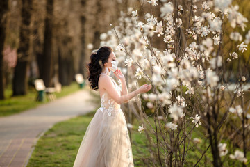 Bride in with a handmade wedding antiviral mask on her face. near a blooming magnolia.  Kovid-19 protects.