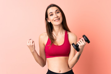 Young sport woman making weightlifting over isolated pink background pointing to the side to present a product