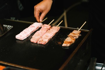 Meat beef skewers grilling on black hot iron pan . Street food concept.