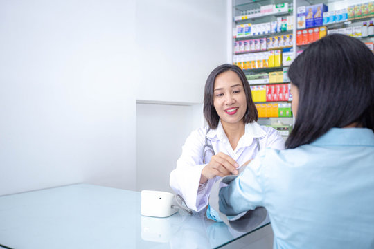 Asian female doctor measuring blood pressure of female patient. Health care insurance concept.