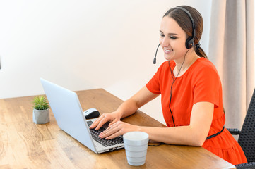 Woman works from home using headset and laptop