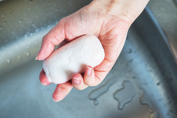 woman holds soap in her hand over the sink. concept treating the skin of hands from viruses and microbes.