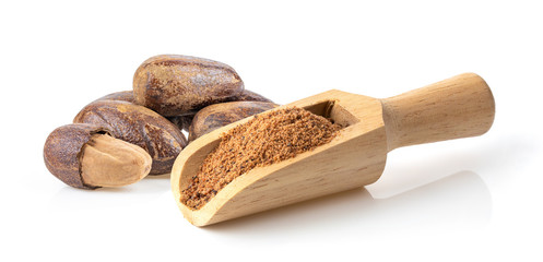 Nutmeg powder in wood scoop on white background