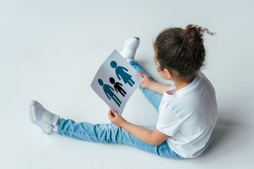 overhead view of curly african american kid holding paper with drawn family on white, adoption concept
