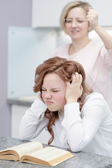 Mom is about to hit her teenager daughter. A teenage girl covers her ears with her hands and ignores her mother. The concept of problems in the relationship between mom and daughter