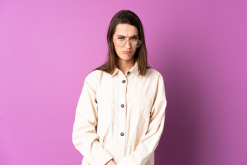 Young woman over isolated purple background with sad expression