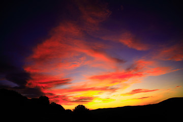 Fototapeta na wymiar Dark orange sky with clouds in the countryside.