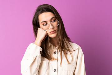 Young woman over isolated purple background with tired and bored expression
