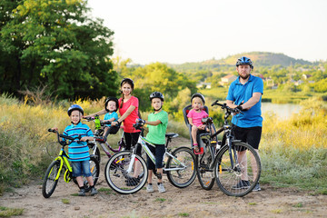 Obraz premium Young large family on bicycles in the Park against the background of greenery and trees.