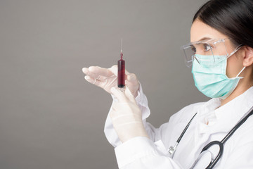 Doctor woman with surgical mask is holding hypodermic syringe