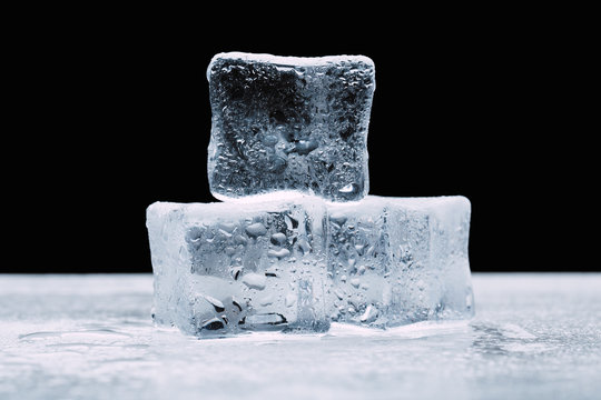 wet ice cubes with drops on a dark black background